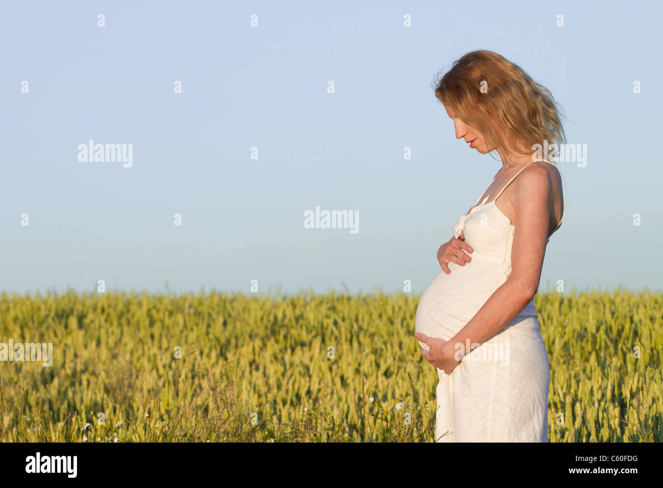 pregnant woman in white dress relaxing outdoors Stock Photo - Alamy