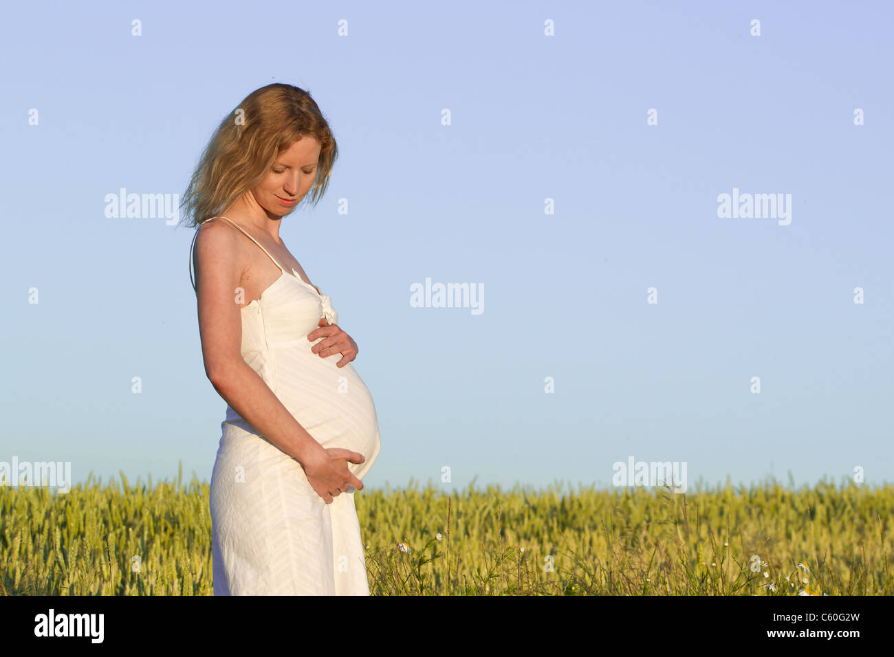 pregnant woman in white dress relaxing outdoors Stock Photo - Alamy