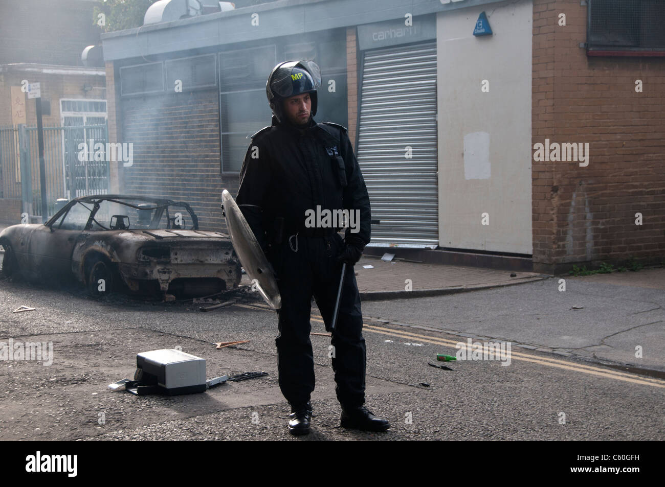 Ellingfort Road. Riot policeman on duty outside Carhartt Warehouse after it  was looted and a car burnt in front of it Stock Photo - Alamy