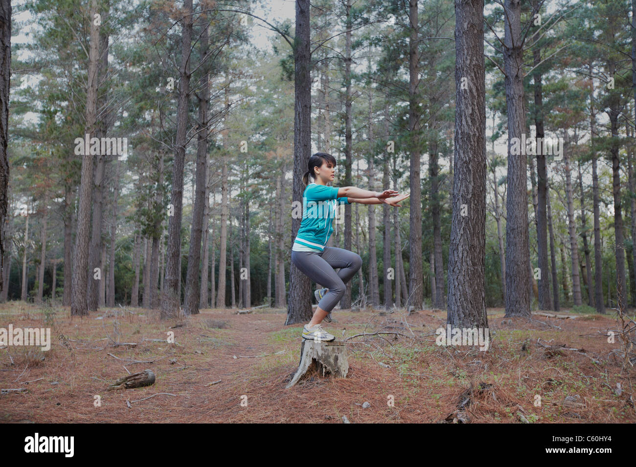 Woman balancing on stump in forest Stock Photo