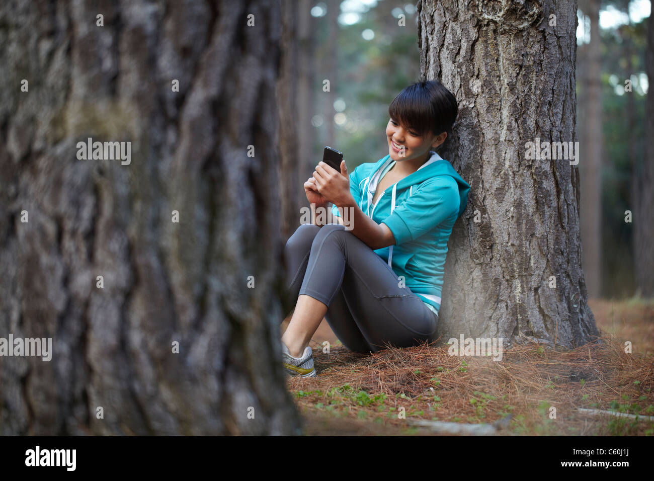 Runner using cell phone in forest Stock Photo