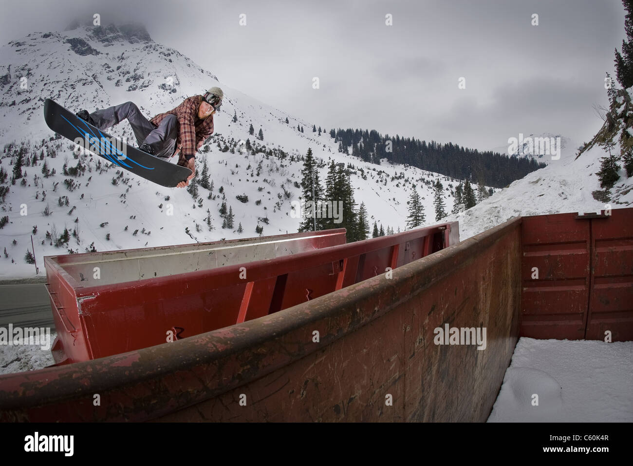 Snowboarder jumping over train cars Stock Photo