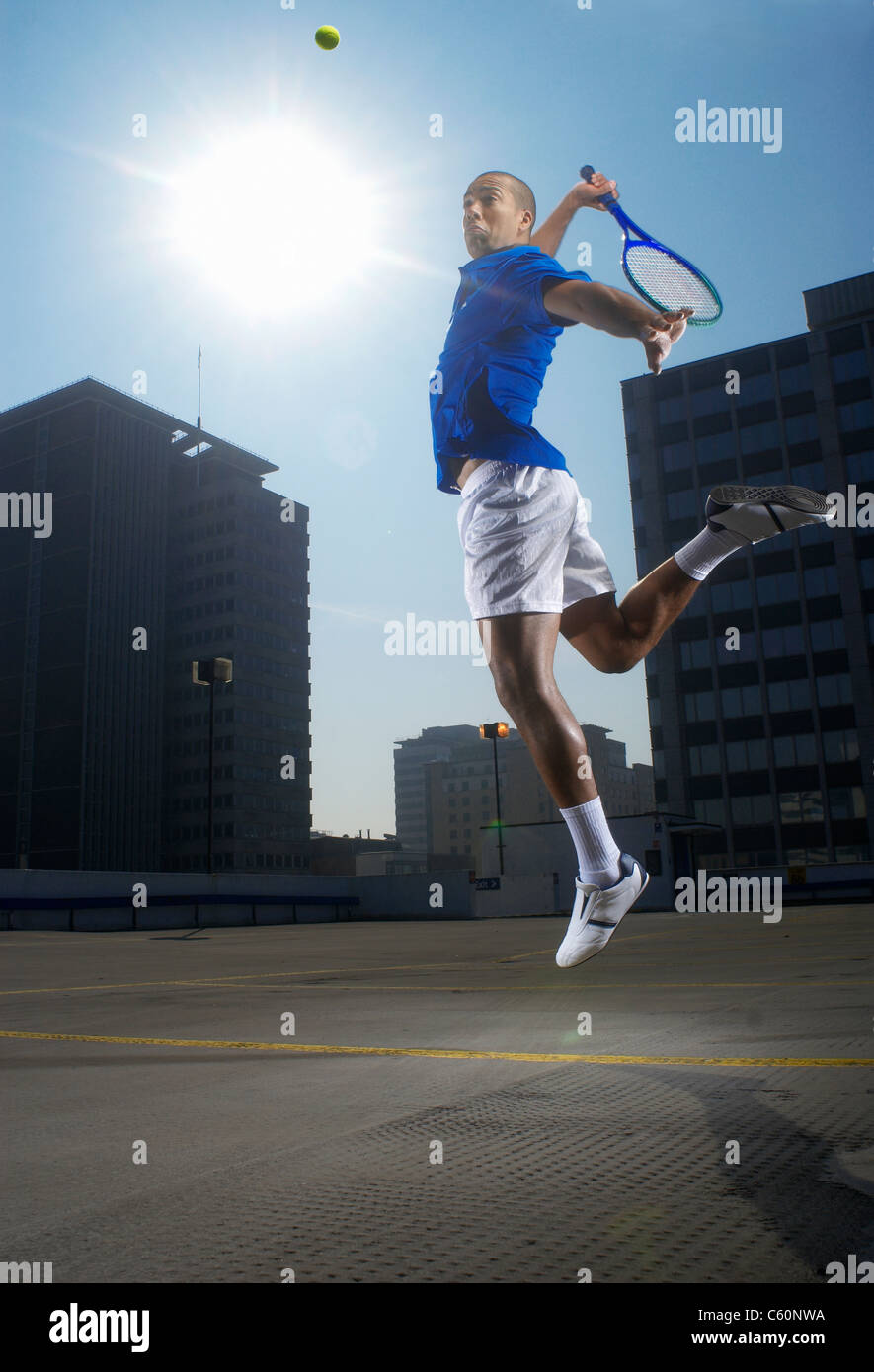 Tennis player jumping on rooftop court Stock Photo