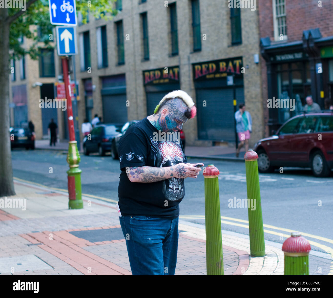 Heavily tattooed man checking his phone near the Chinese Quarter in Birmingham. Stock Photo