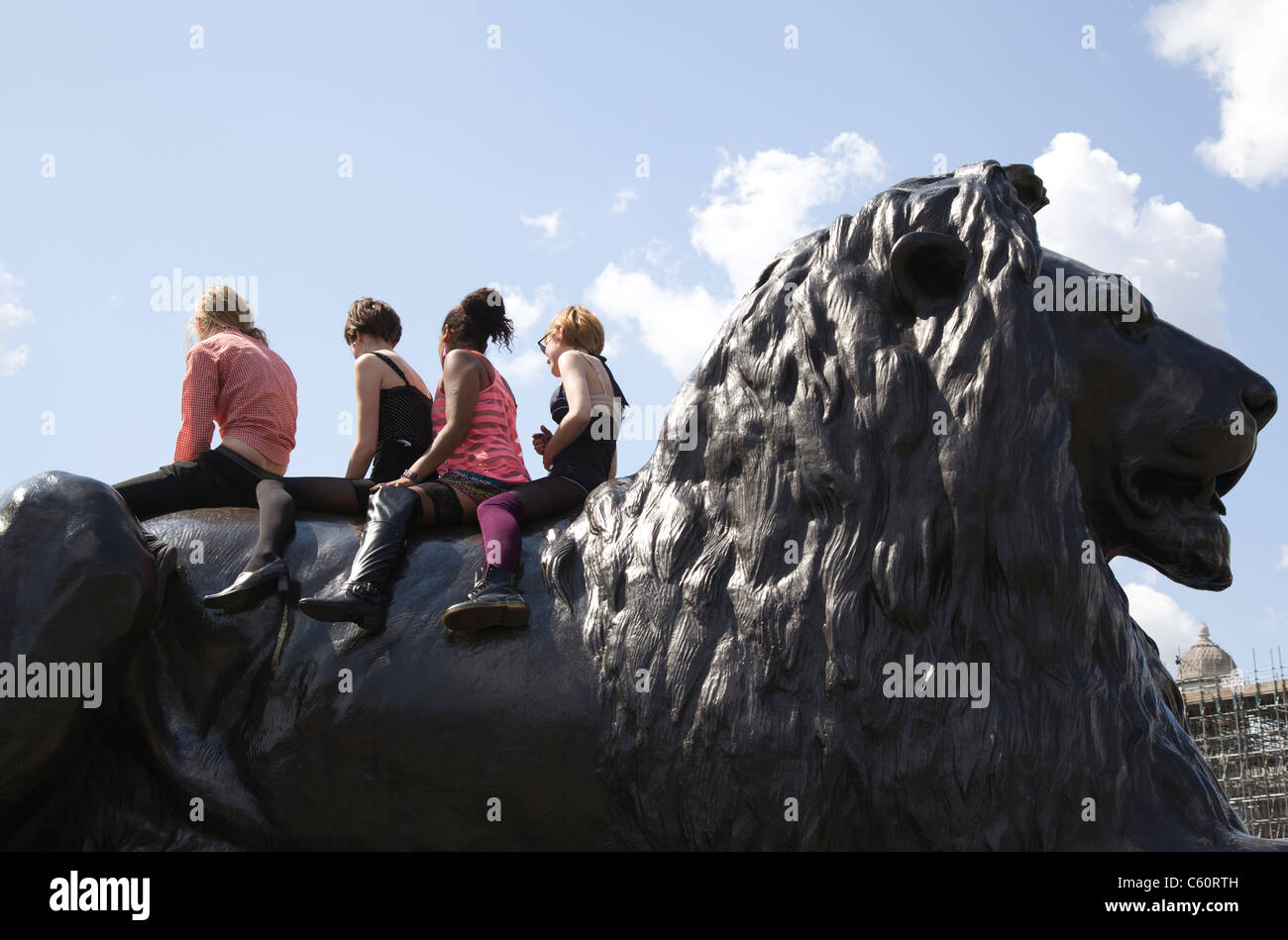Four anonymous children sit on the back of a lion statue in London's Trafalgar Square Stock Photo