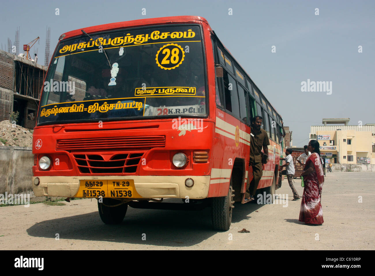 Woman passenger boards Tamil Nadu State Express bus departing from bus station in Krishnagiri, Tamil Nadu, India Stock Photo