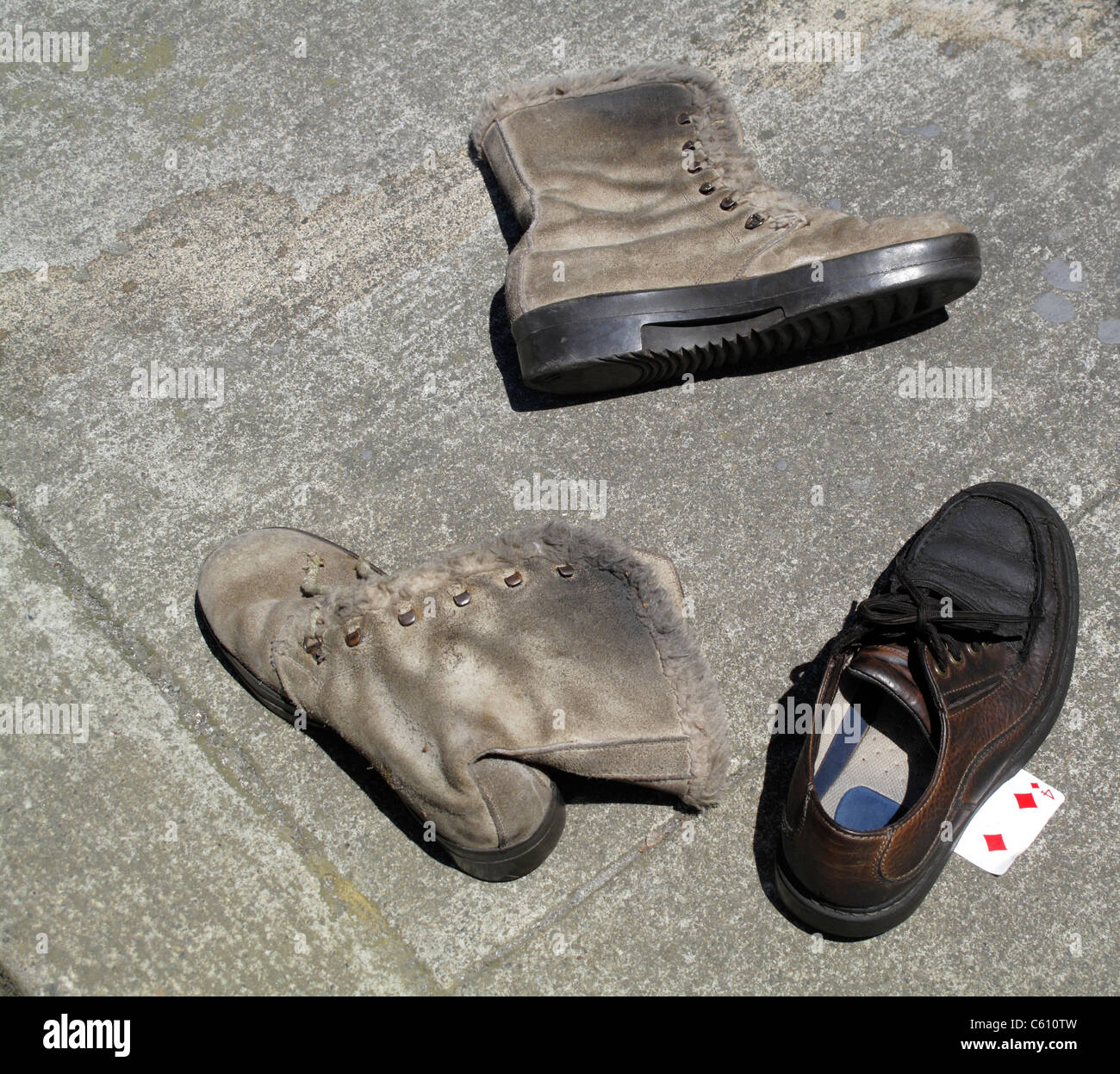 Three abandoned shoes on sidewalk with four of diamonds playing