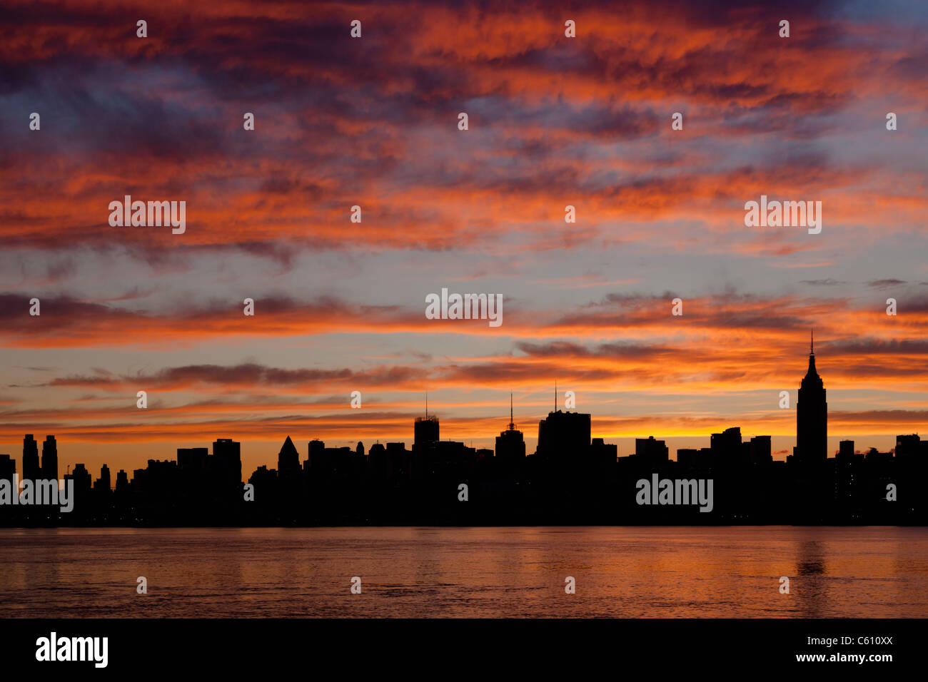 The sky begins to lighten and clouds reflect pre-sunrise color over the midtown Manhattan skyline in New York City. Stock Photo