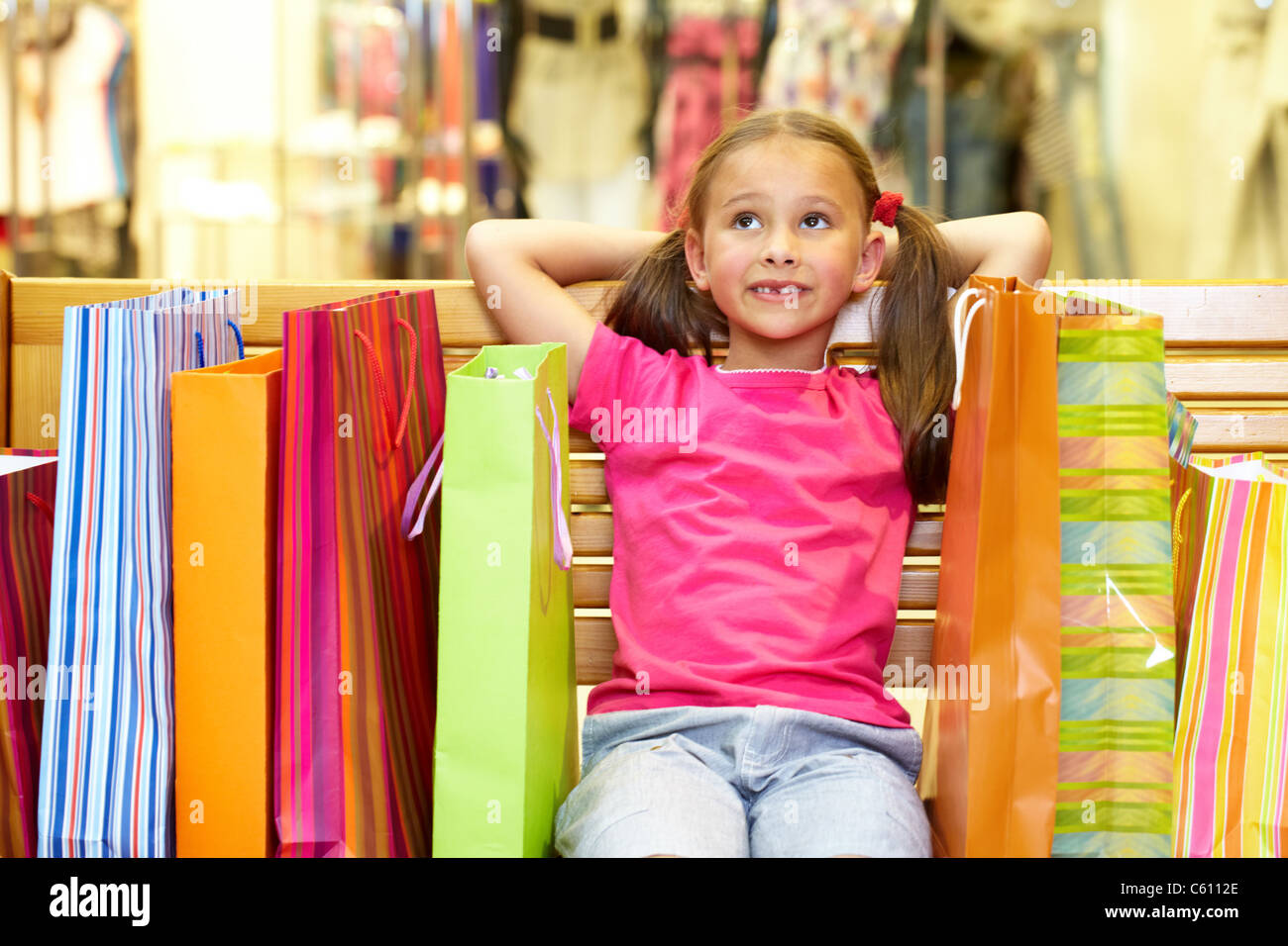 A little girl sitting on bench with plenty of shopping bags Stock Photo ...