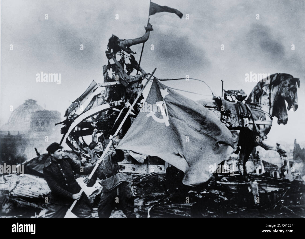 Russian soldiers raise the Soviet Flag next to the battered sculptures of the Brandenburg Gate in the final European battle of World War II. May 2, 1945 photo by Evgenii Khaldei. Stock Photo