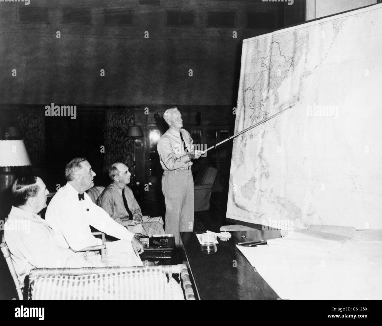 President Roosevelt meeting with General Douglas MacArthur, Admiral William D. Leahy, and Admiral Chester W. Nimitz, who is pointing to Tokyo on a large map. August 1944. Stock Photo