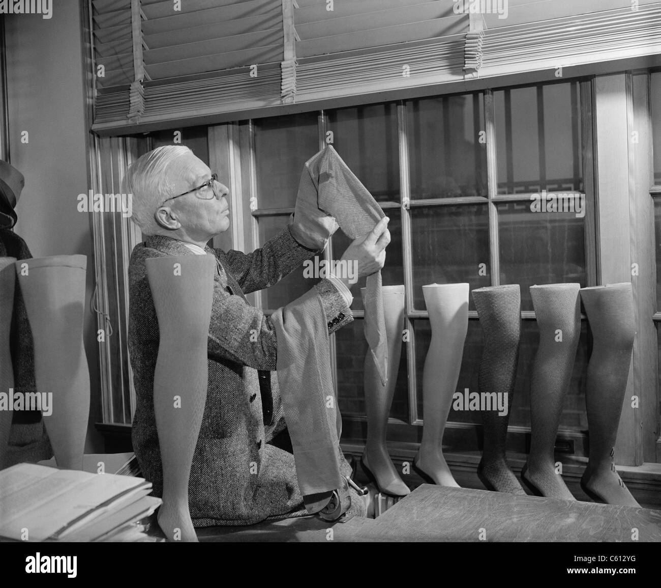Agriculture Department fabric technician examines the cotton stockings that would replace those made by Japanese silk, after FDR froze all Japanese credits in the United States in response to the Japanese occupation of French Indo-China. The stocking industry had only two months supply of silk and nylon production was in it's infancy. July 1941. Stock Photo
