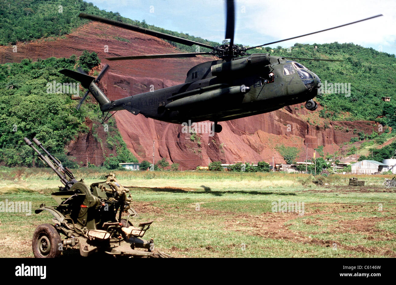 U.S. Marine Corps helicopter hovers near a Soviet anti-aircraft weapon during the U.S. invasion of Grenada in October 1983. The Stock Photo