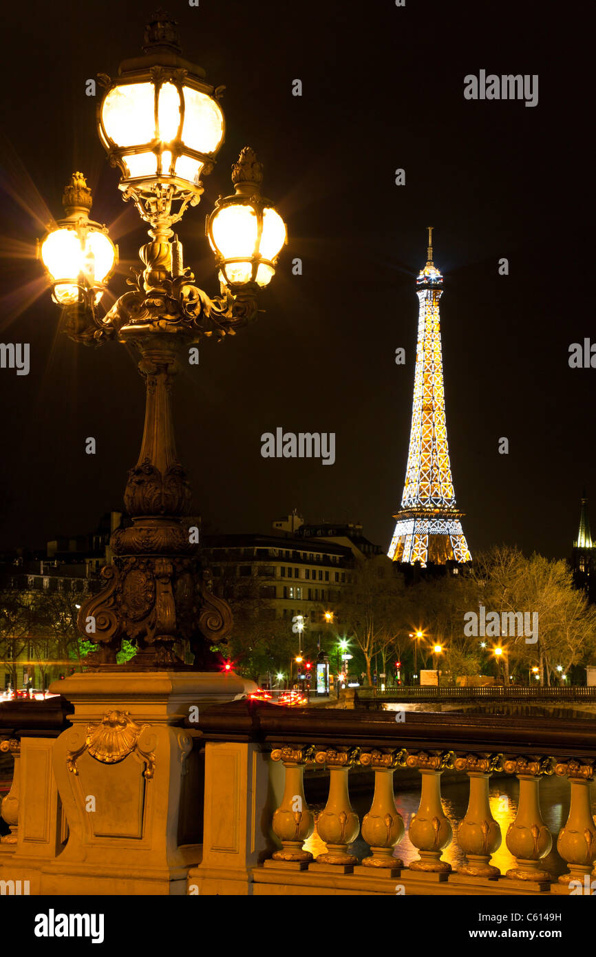 Lamppost on the bridge of Alexander III, against the backdrop of the Eiffel Tower at night. Paris, France. Stock Photo
