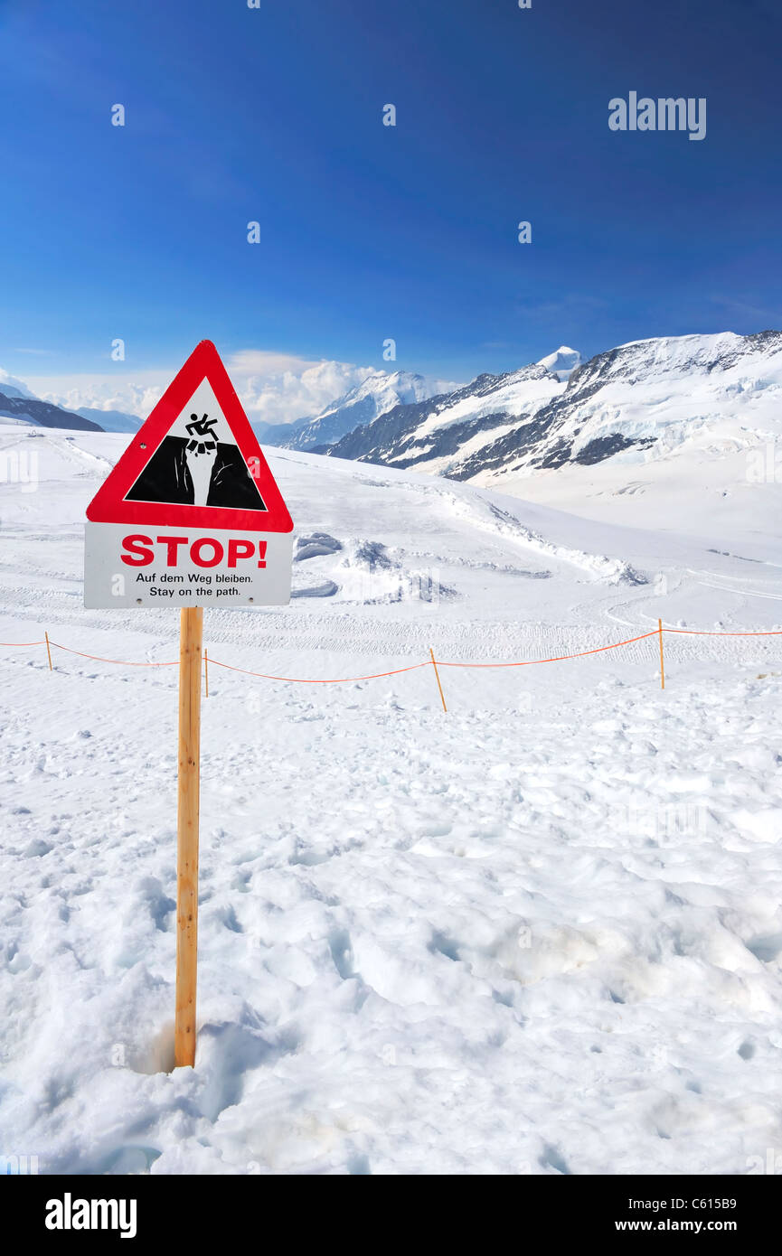 A sign at the top of the Aletsch Glacier warning walkers not to venture further. Space for text in the sky. Stock Photo