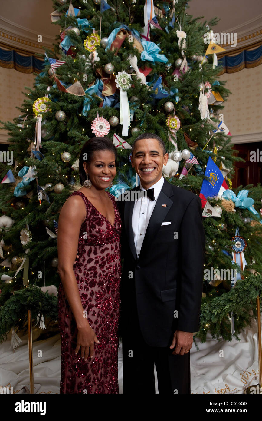 President and Michelle Obama pose in front of the Official White House Christmas Tree Dec. 5 2010. Michelle wears a scarlet floral sequined gown by Naeem Khan and earrings of rough diamonds in oxidized white gold by Bochic., Photo by: Everett Collection(BSLOC 2011 7 145) Stock Photo