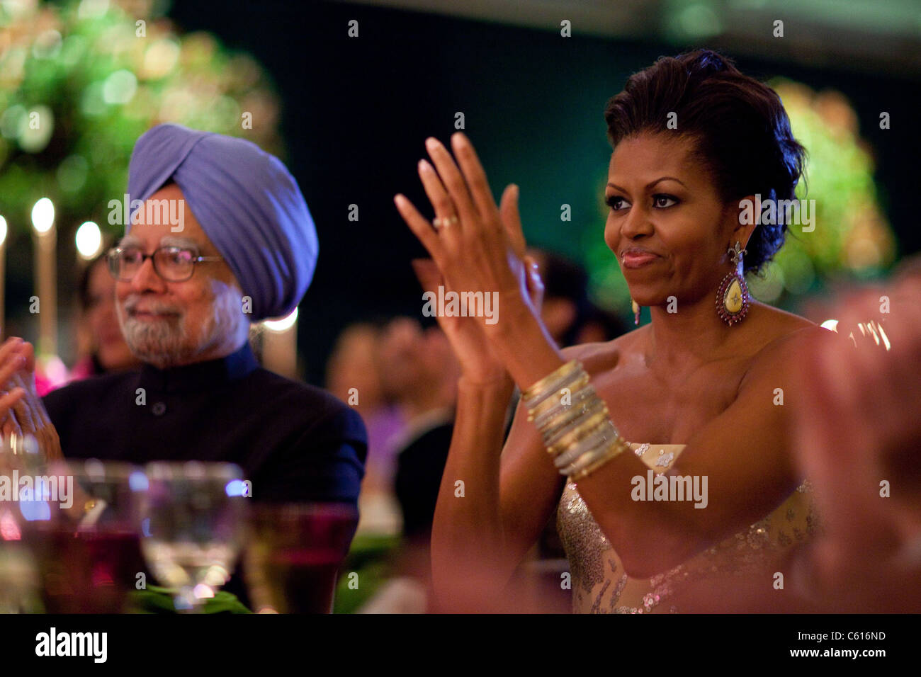 Michelle Obama applauds during the State Dinner for Prime Minister Manmohan Singh of India and his wife Mrs. Gursharan Kaur. Michelle's wears Bochic earrings of rose cut diamonds amber and tourmaline stones and bangle bracelets., Photo by: Everett Collection(BSLOC 2011 7 90) Stock Photo