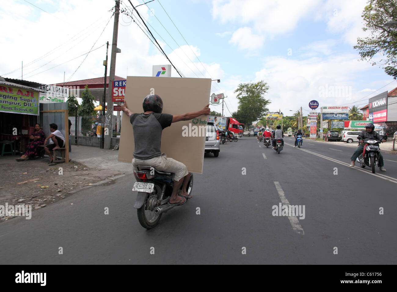 Passenger on motorbike holding a piece of plasterboard. Stock Photo