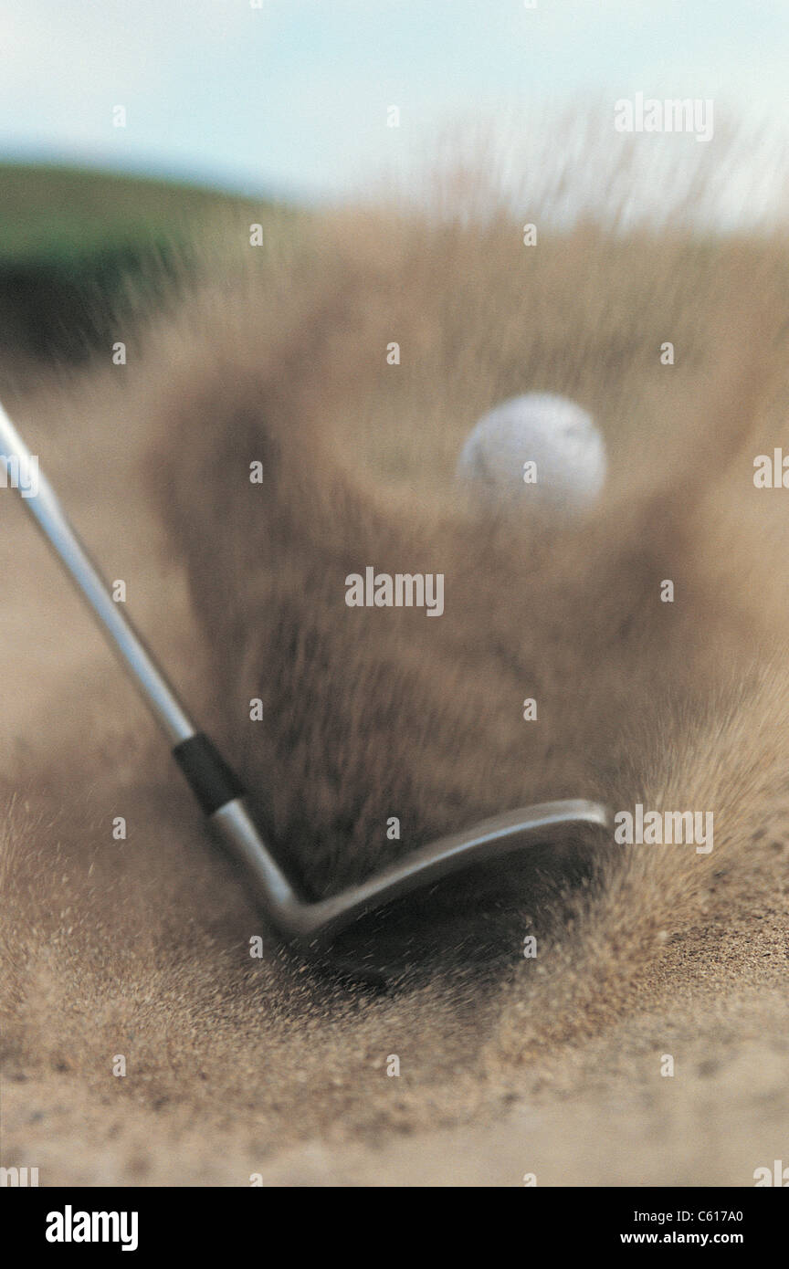 Macro of a golf ball being being struck by a club in a bunker, with flying sand Stock Photo