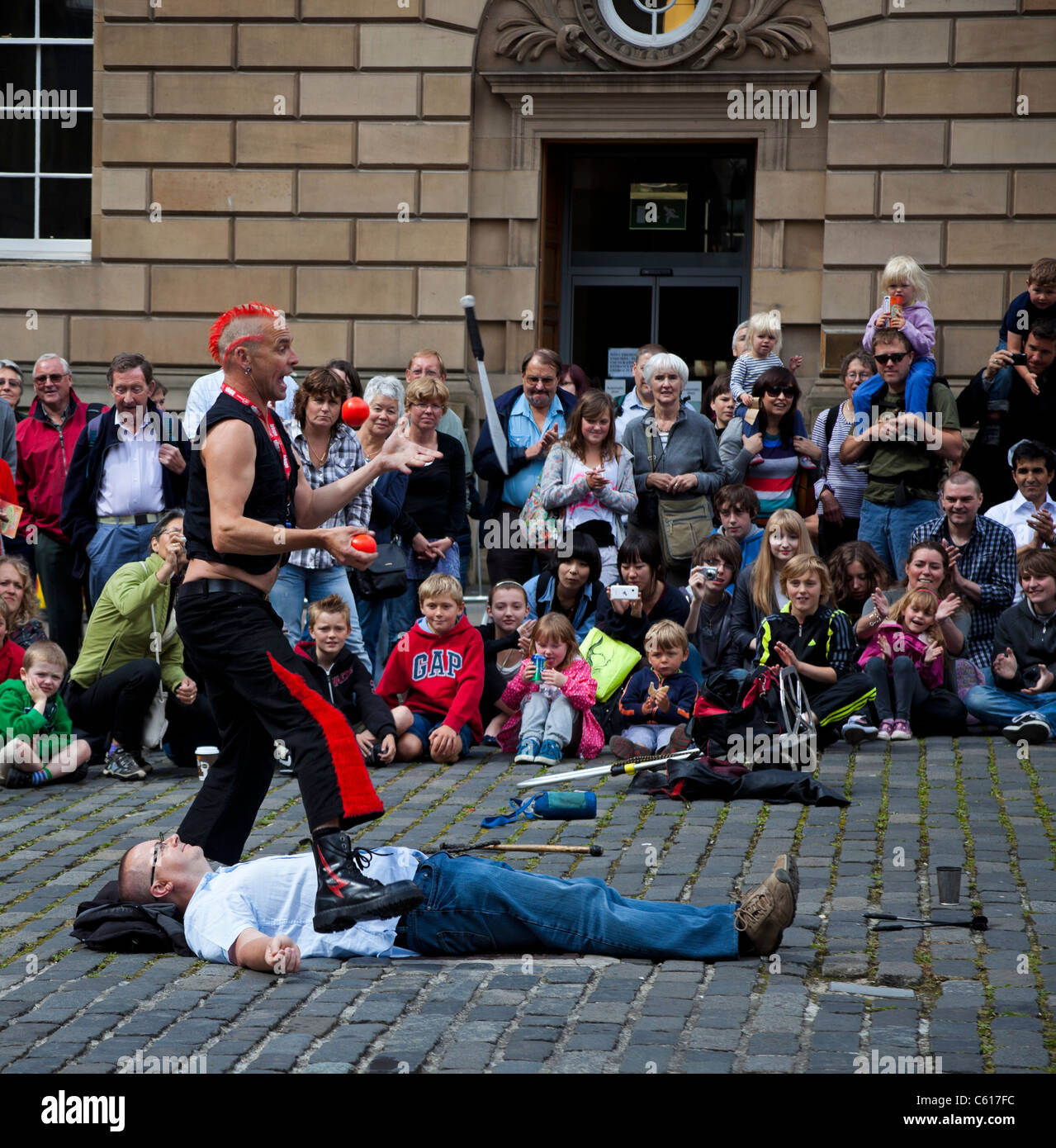 Mighty Gareth Edinburgh Fringe Festival Street Performer juggling knive and balls above volunteer 2011 Stock Photo