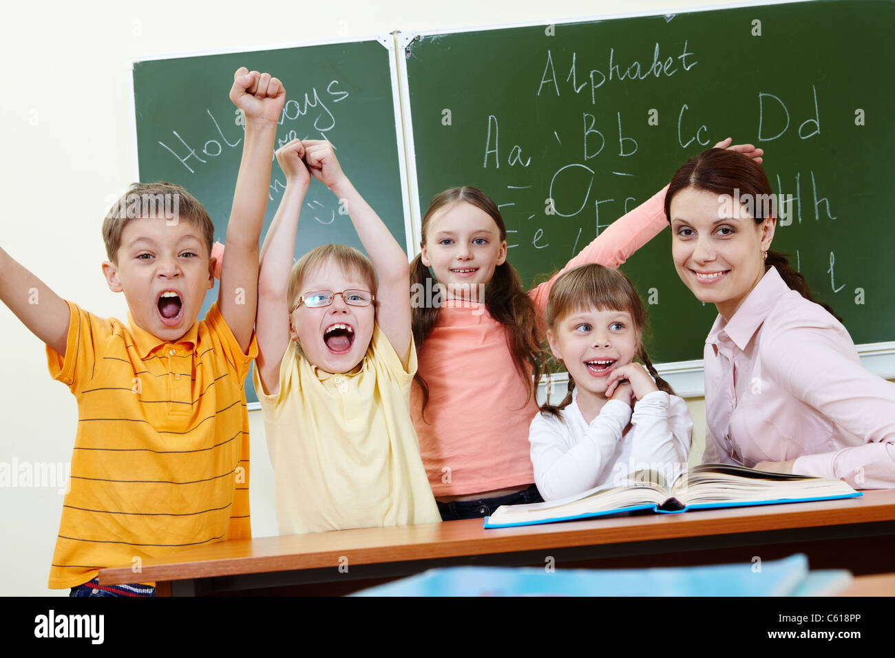 Portrait of joyful schoolchildren showing gladness with their teacher near by Stock Photo