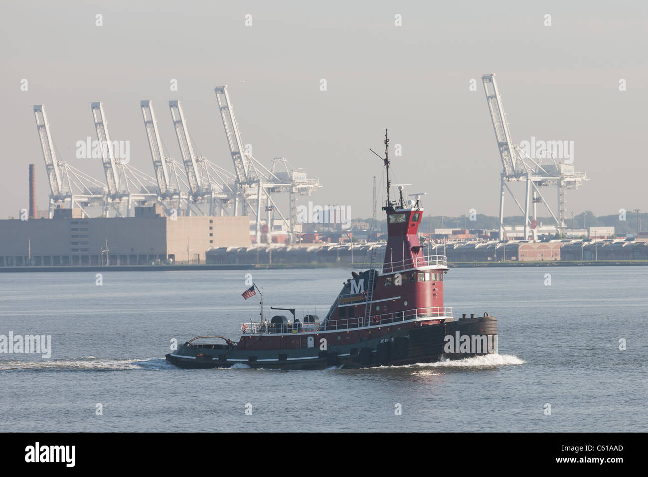 Tugboat 'Jean Turecamo' heads north in New York Harbor, with the Global Terminal container cranes in the background. Stock Photo