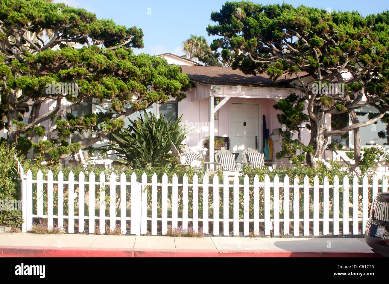 Beach house with cypress trees in the yard and a white picket fence in La Jolla, California Stock Photo