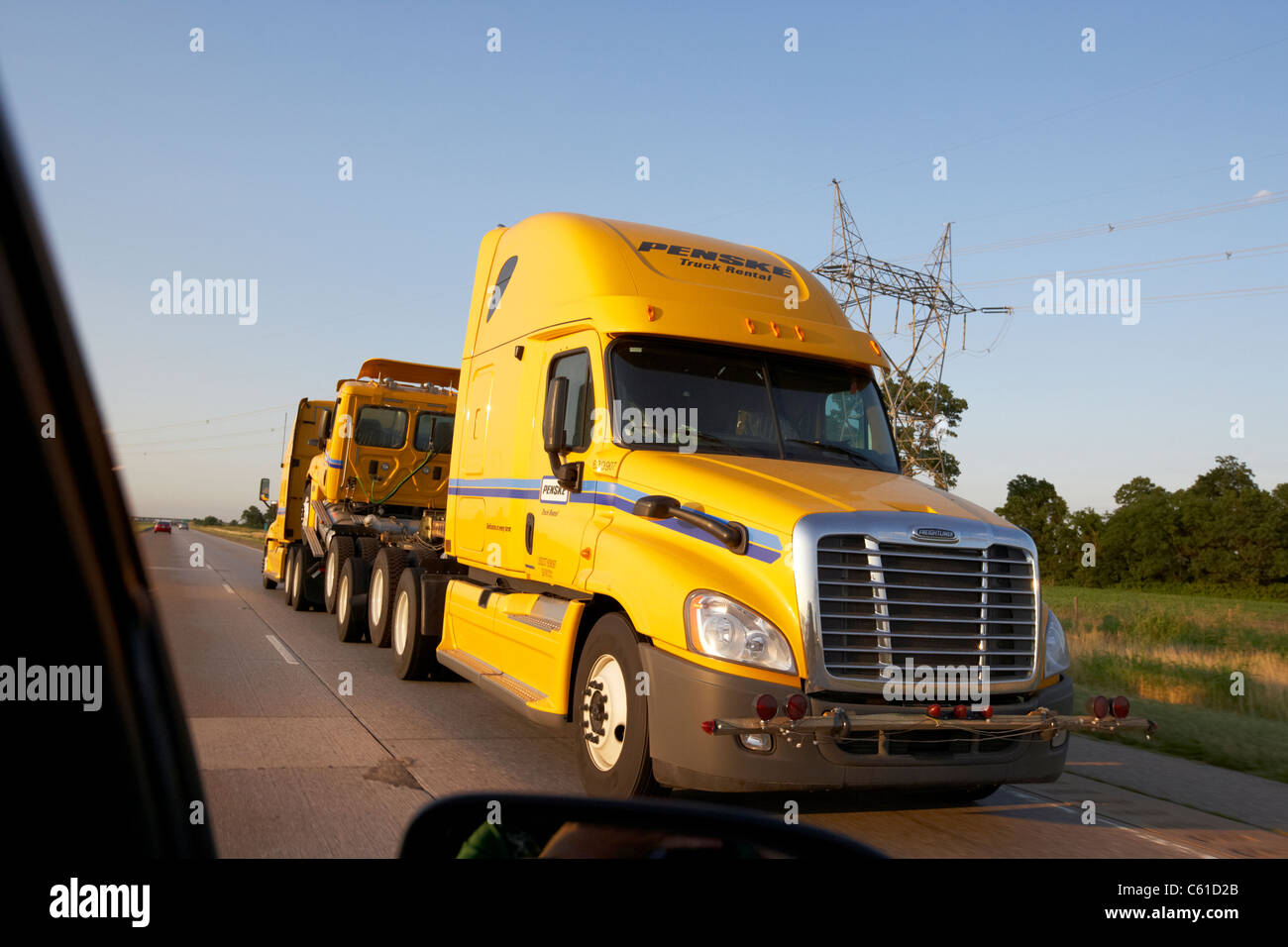 passing semi truck delivering other tractor units while driving along a highway in the usa Stock Photo