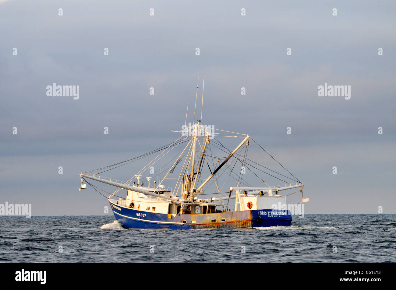 Blue hulled trawler fishing boat off the coast of Cape Cod in Buzzards Bay, USA with outriggers extended for trawling nets for fish Stock Photo