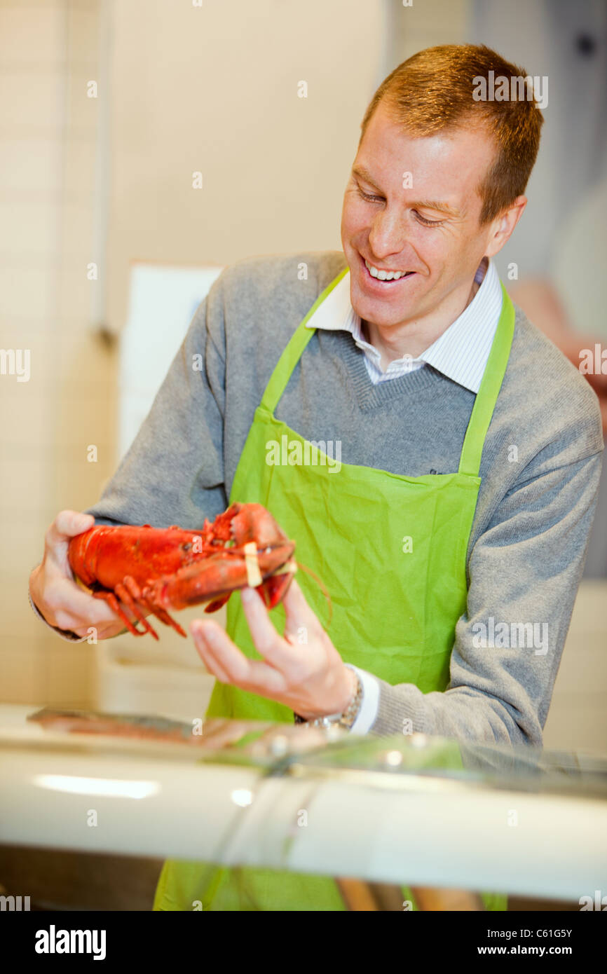 A grocery store worker with a lobster at the fish counter Stock Photo
