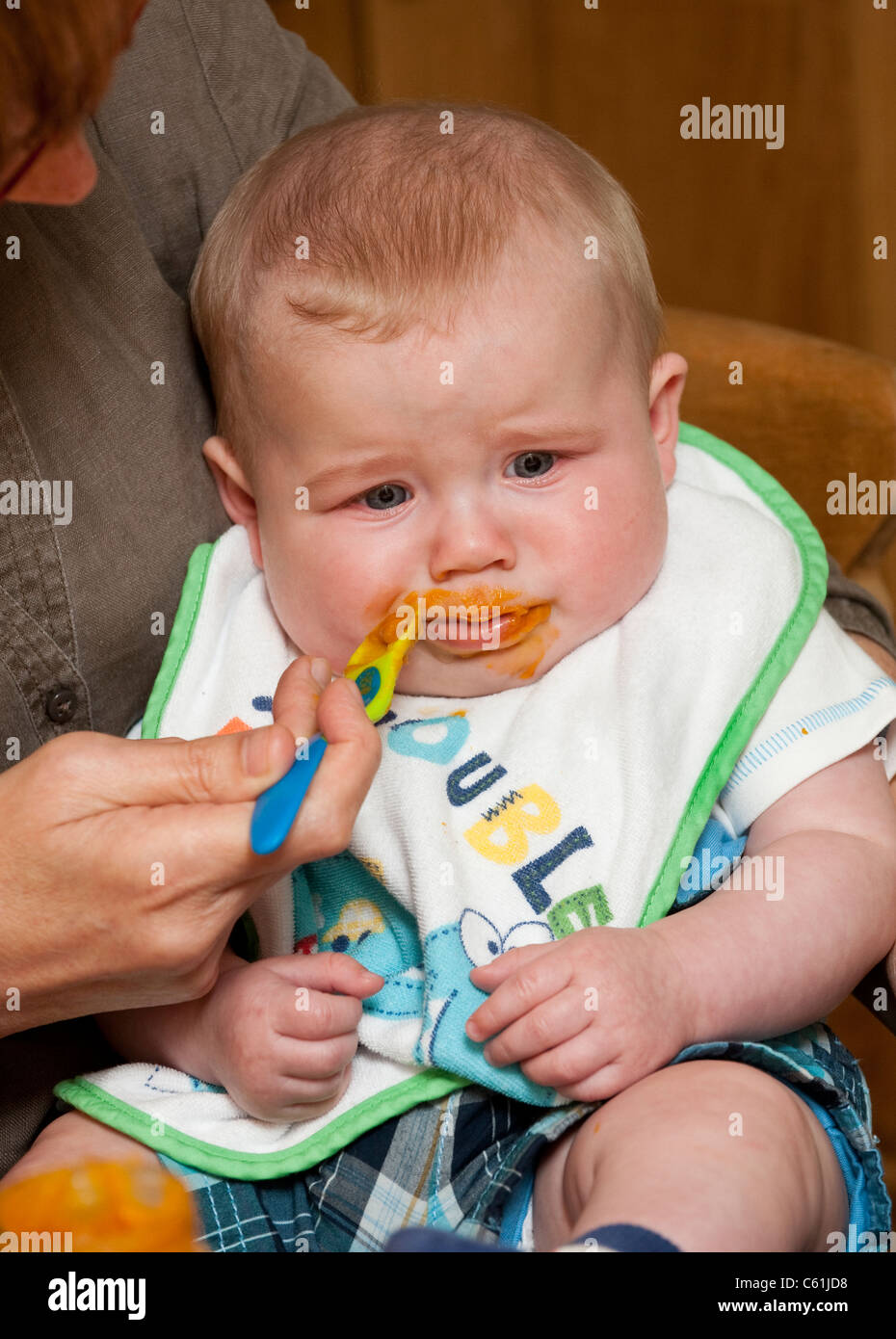 Unhappy baby boy being spoon fed at mealtime Stock Photo - Alamy
