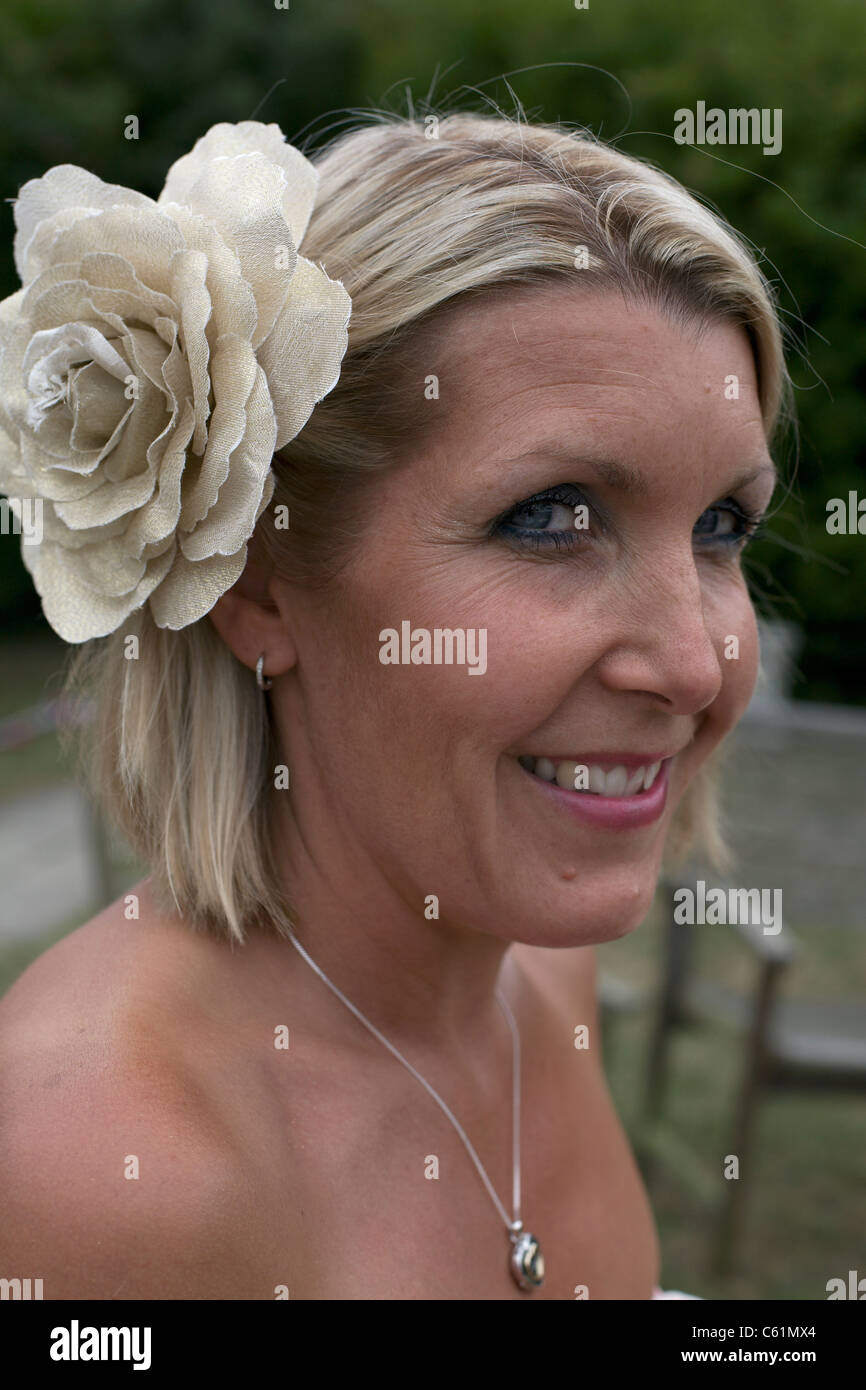 English woman with an ornamental flower in her hair smiling at her 40th birthday party Stock Photo