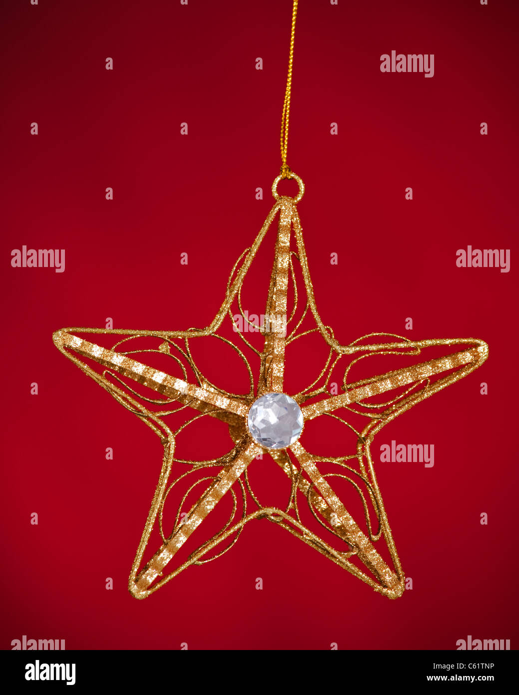 A gold Christmas tree star ornament isolated against a red background ...