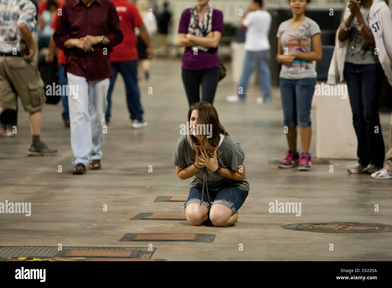 Young white woman on her knees while praying at a Christian faith all-day prayer event at Reliant Stadium in Houston, Texas Stock Photo