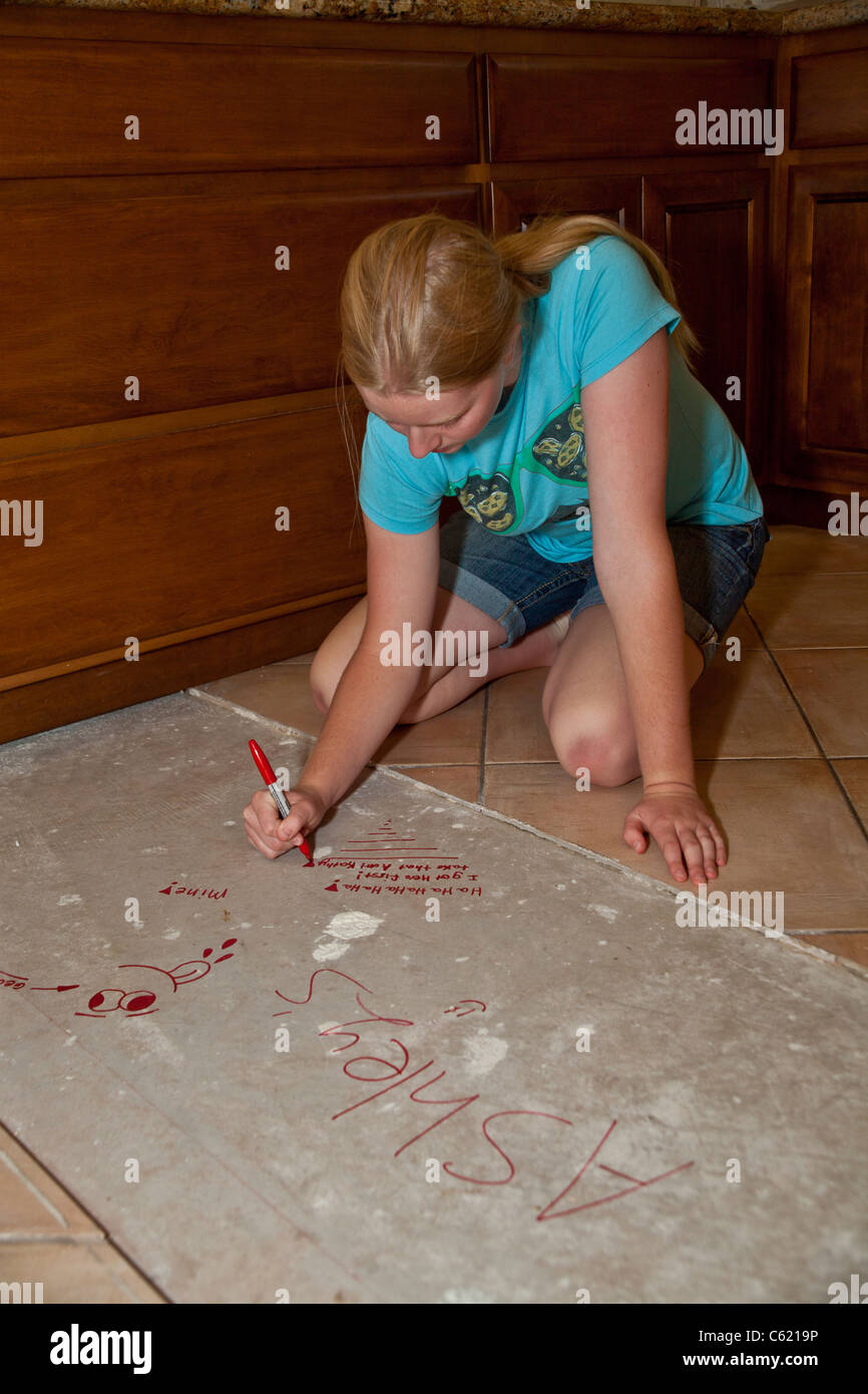 Teen girl writing on unfinished areas of kitchen remodel. MR Myrleen Pearson Stock Photo