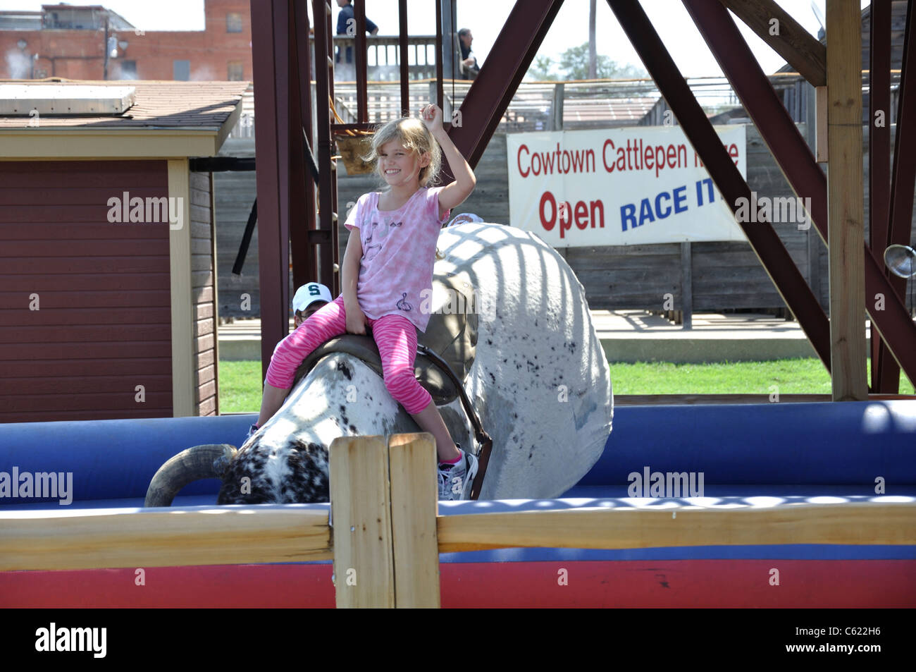 Little girl on mechanical bull ride, Stockyards, Fort Worth, Texas, USA Stock Photo