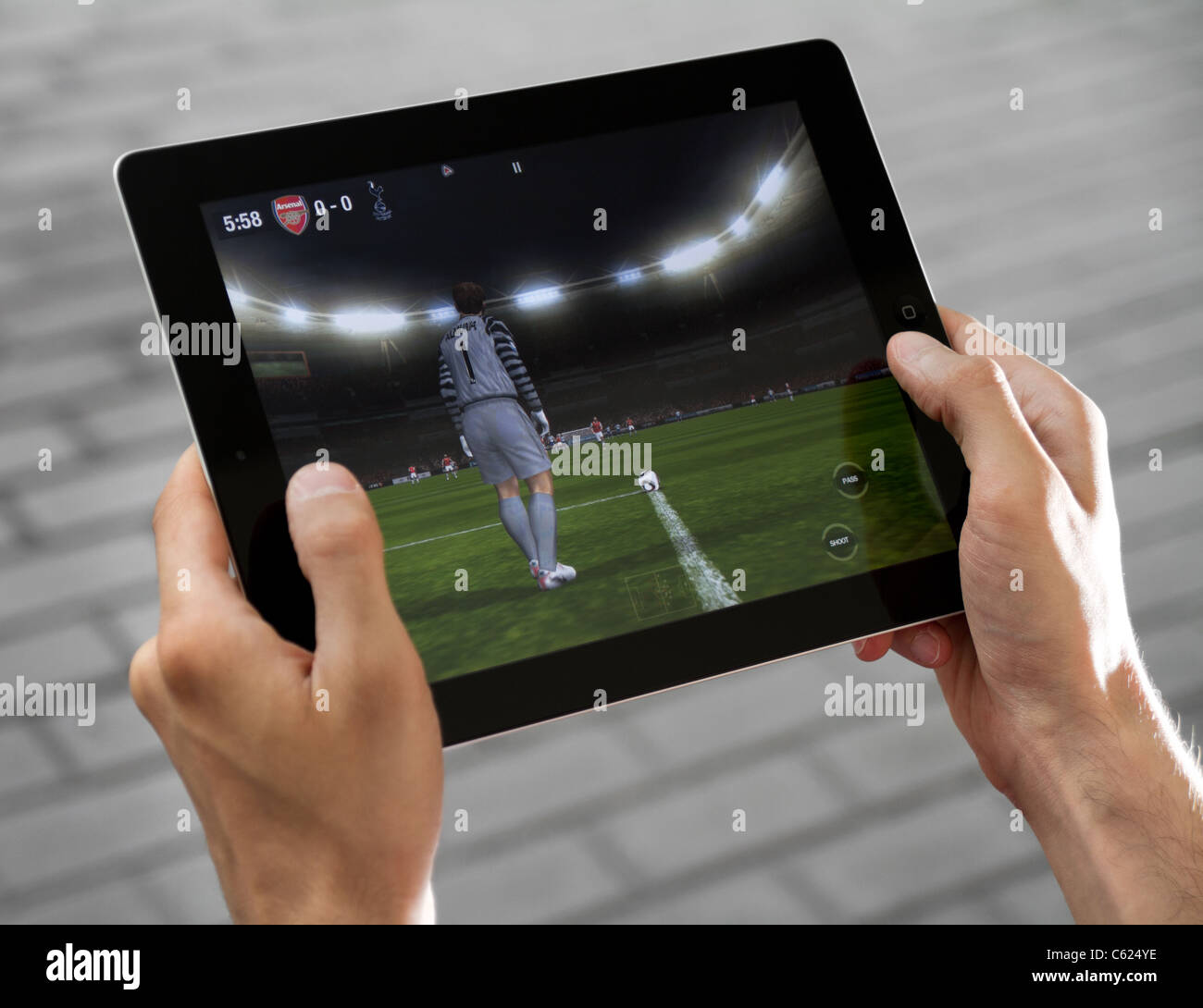 A man outdoors play in the game FIFA football on Apple Ipad2 Stock Photo