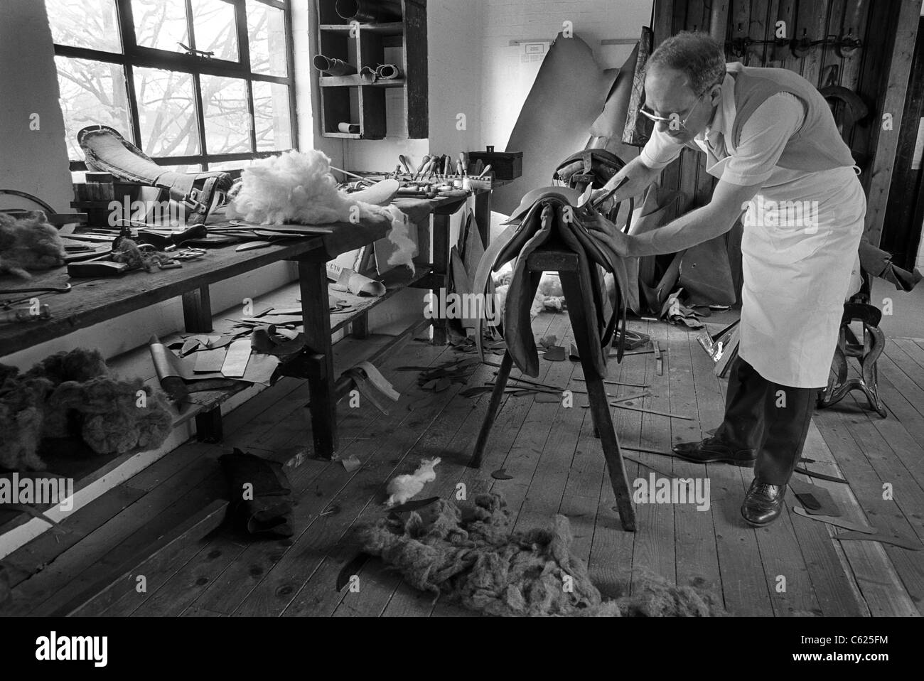 Master saddler Frank Baines at work in his Walsall workshop making a horse's saddle. vintage black and white image. Stock Photo