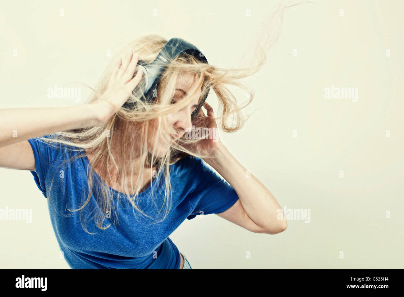 young woman singing with headphones on a light background Stock Photo