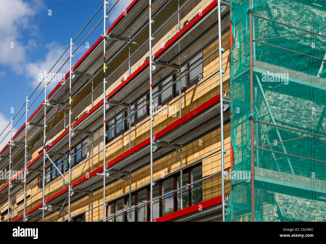 Corner view of a building with scaffolding enclosed in green safety fabric Stock Photo