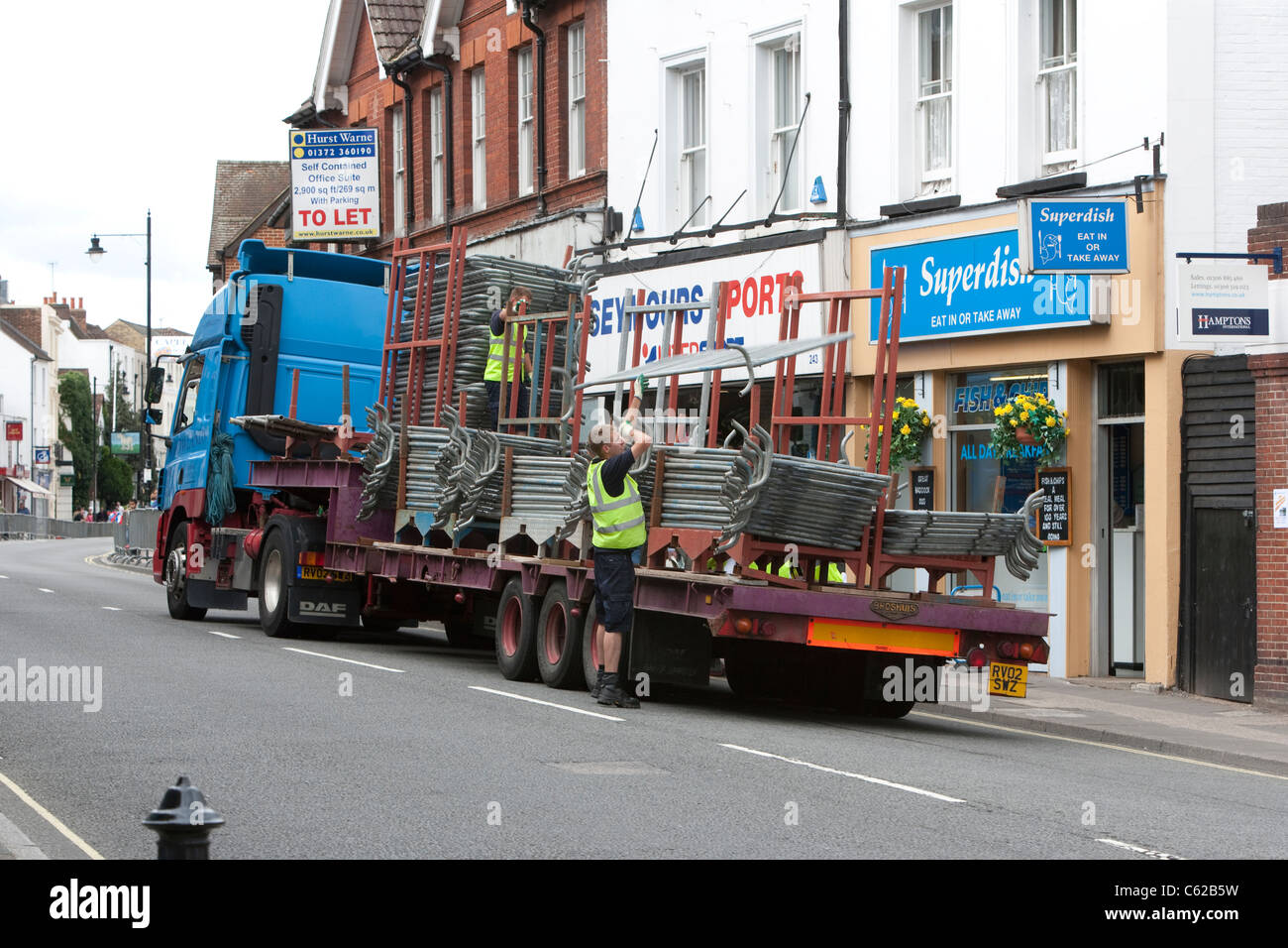 Barriers used for crowd control are collected from the roadside immediately after an event along Dorking High Street, Surrey, UK Stock Photo
