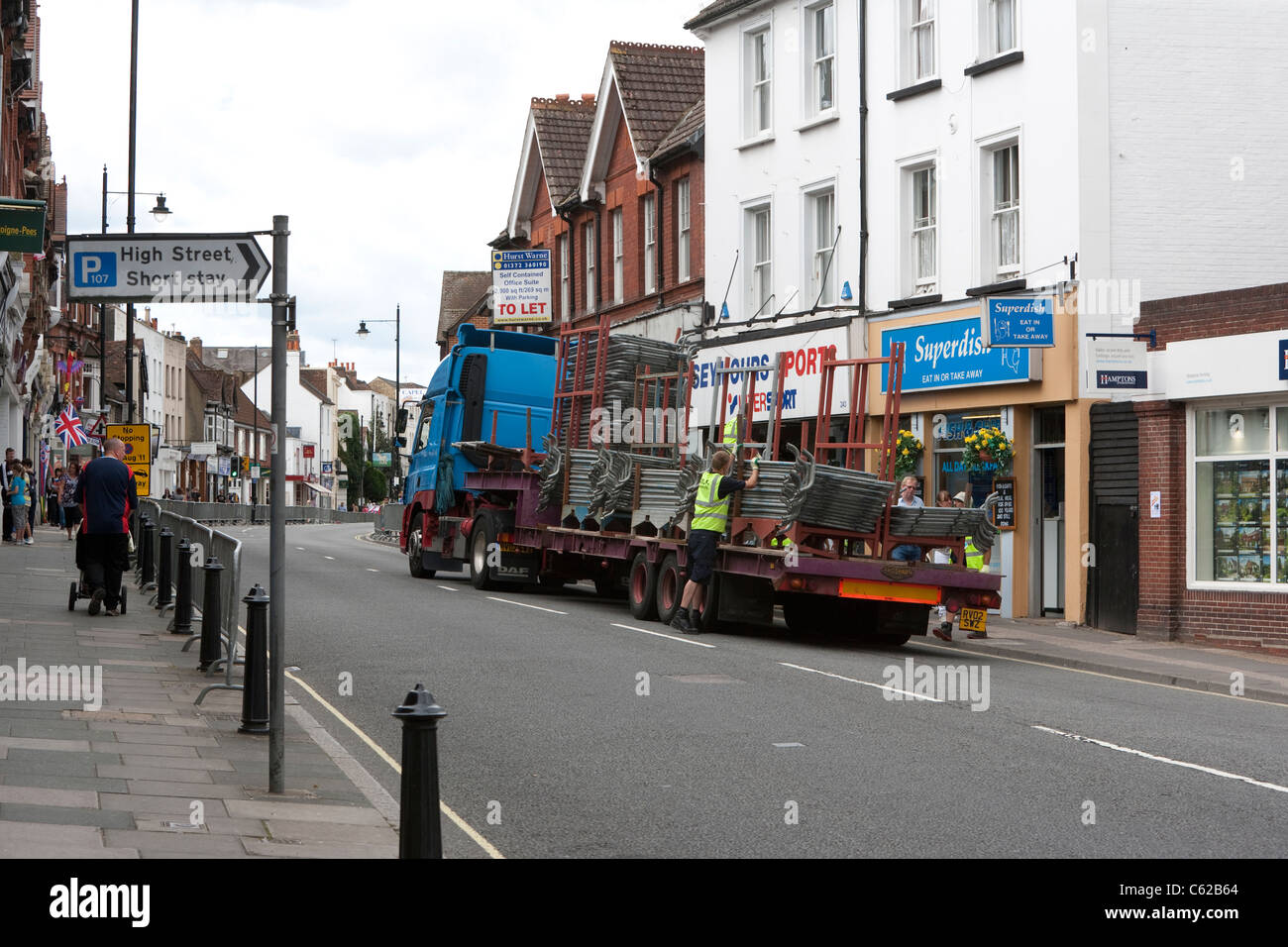 Barriers used for crowd control are collected from the roadside immediately after an event along Dorking High Street, Surrey, UK Stock Photo