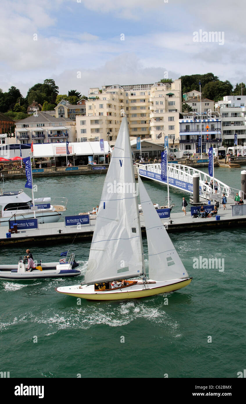 Sailing boat underway on the River Medina during Cowes Week Backdrop of Cowes waterfront Isle of Wight England Uk Stock Photo