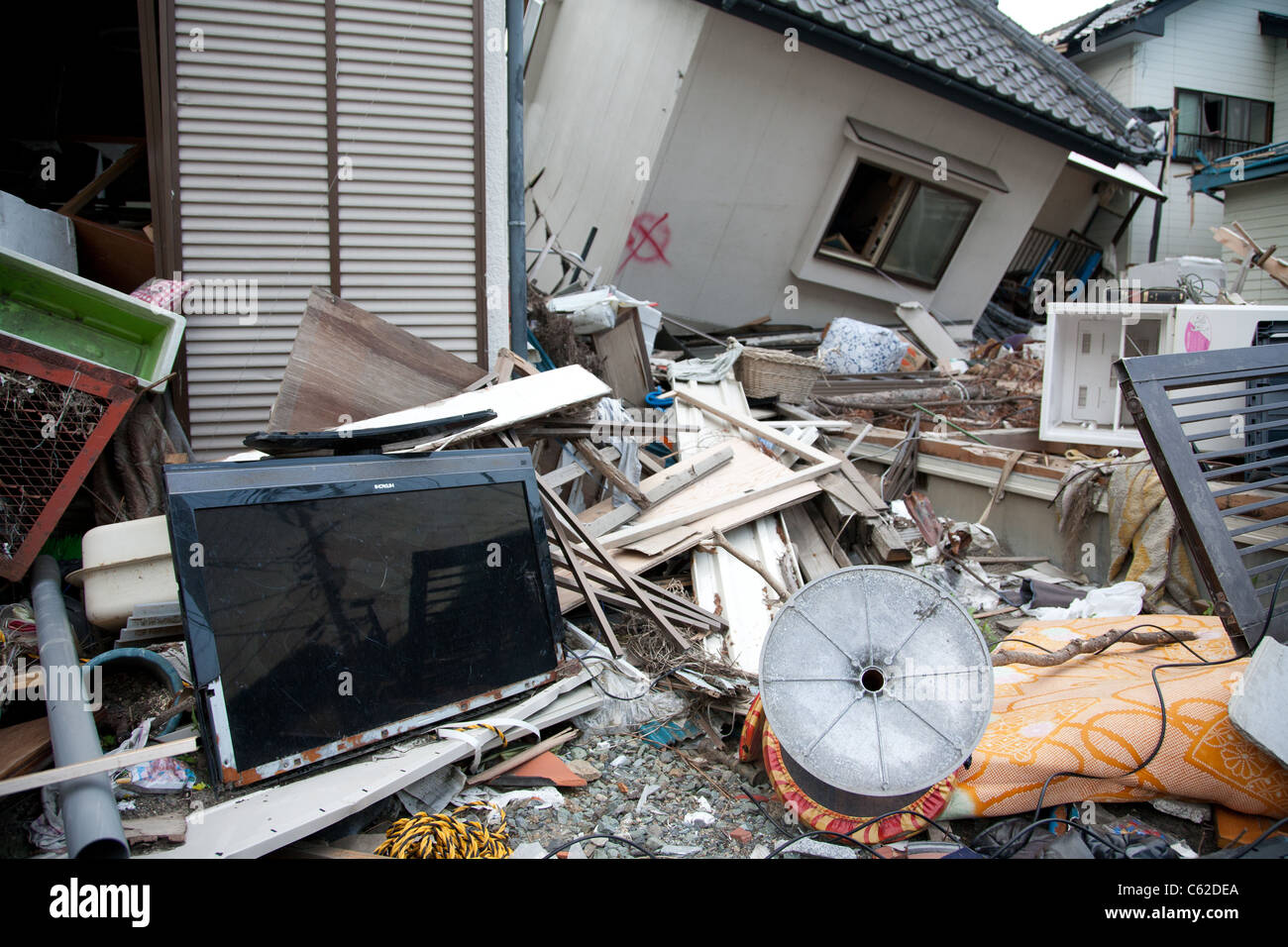 A large flat panel TV sits wrecked in front of homes toppled by the tsunami in Kamaishi, Japan, June 2011 Stock Photo