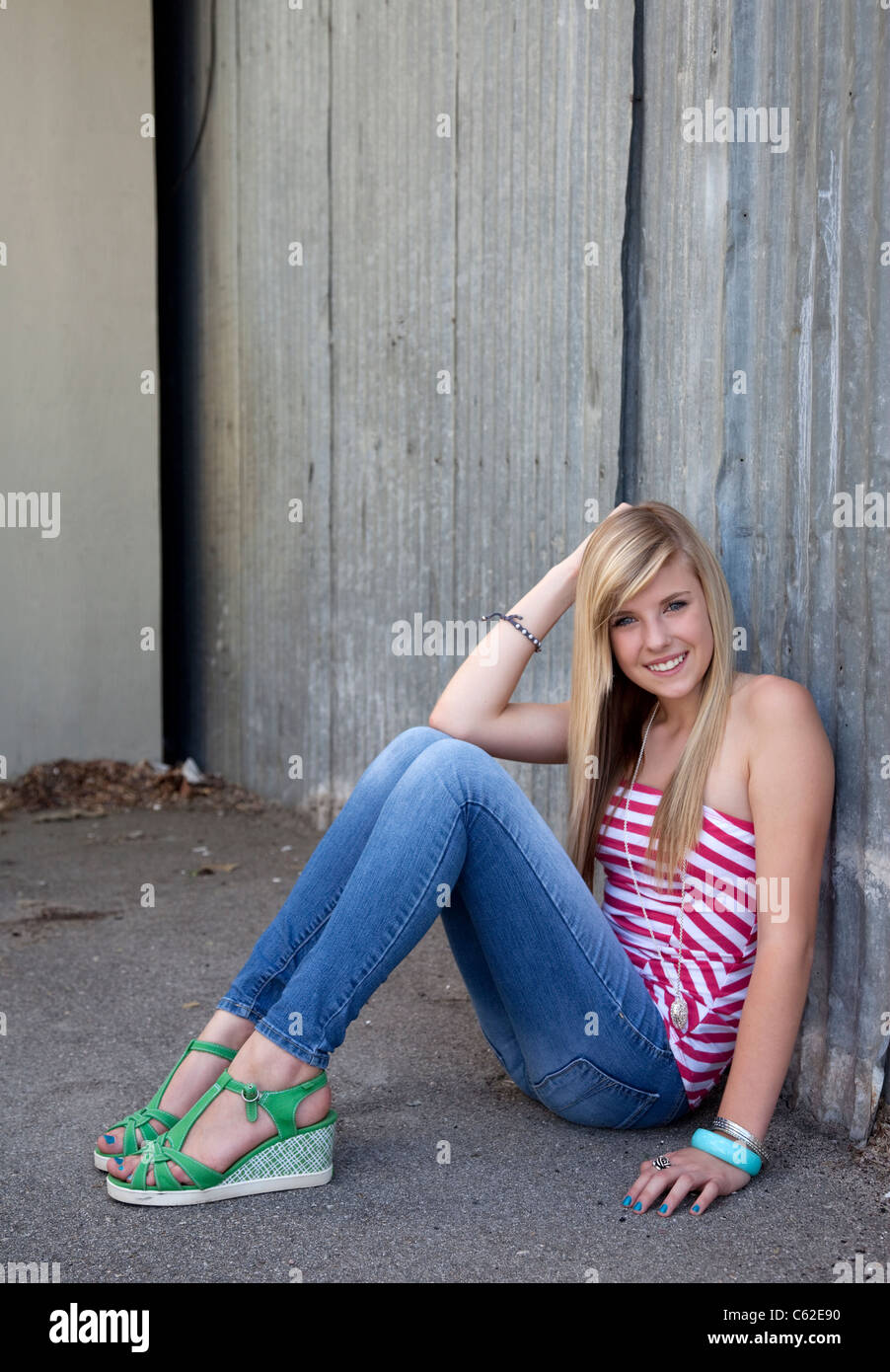 Outdoor photo of pretty teenage girl sitting on the ground in grungy setting. Stock Photo