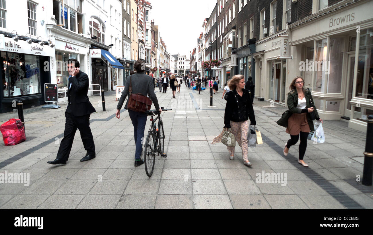 Woman with bicycle and people walking along New Bond Street past shopping boutique shops in West London England UK KATHY DEWITT Stock Photo