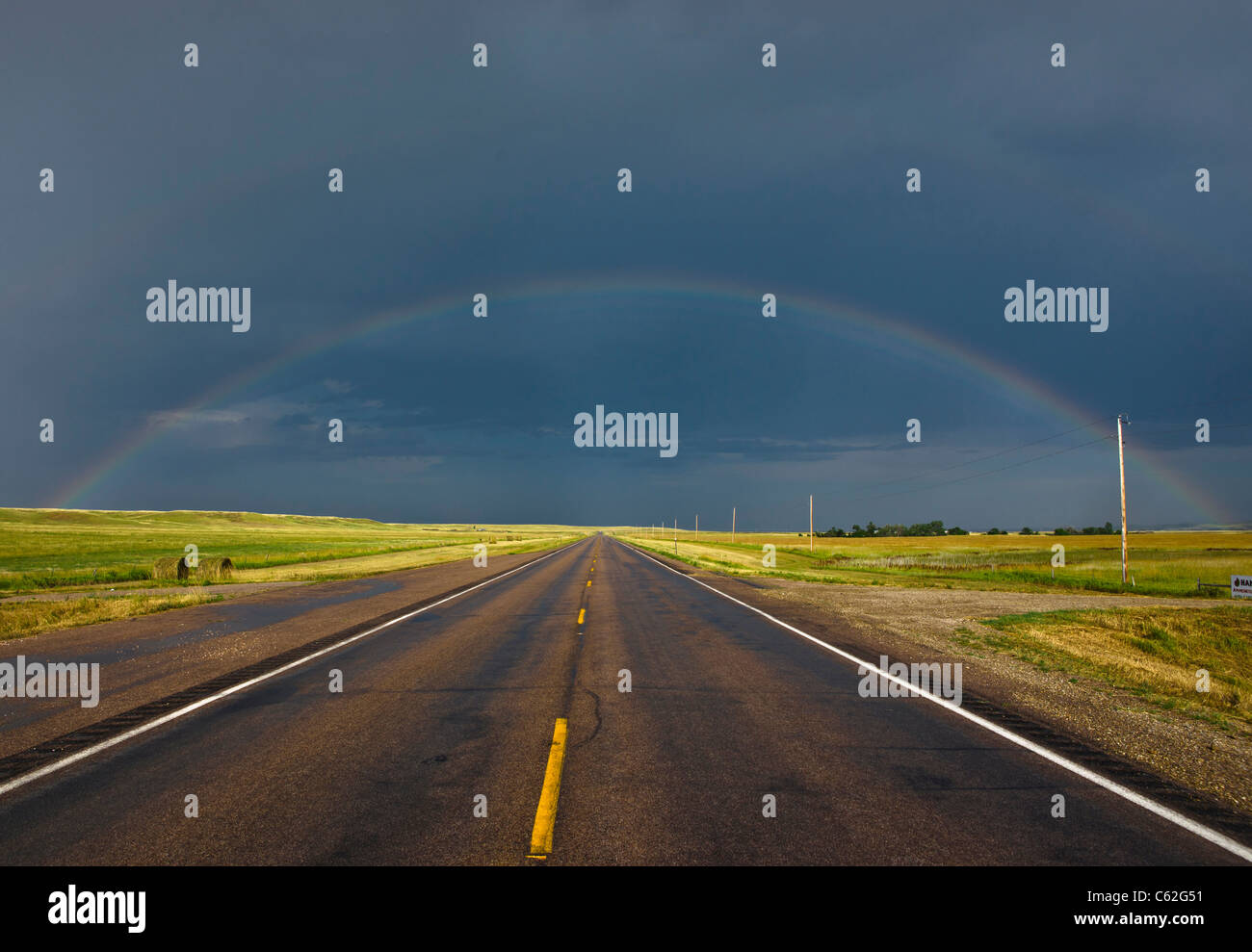 Rainbow against stormy sky over a road on prairies in South Dakota USA US beautiful prairie prairies landscape nobody horizontal hi-res Stock Photo