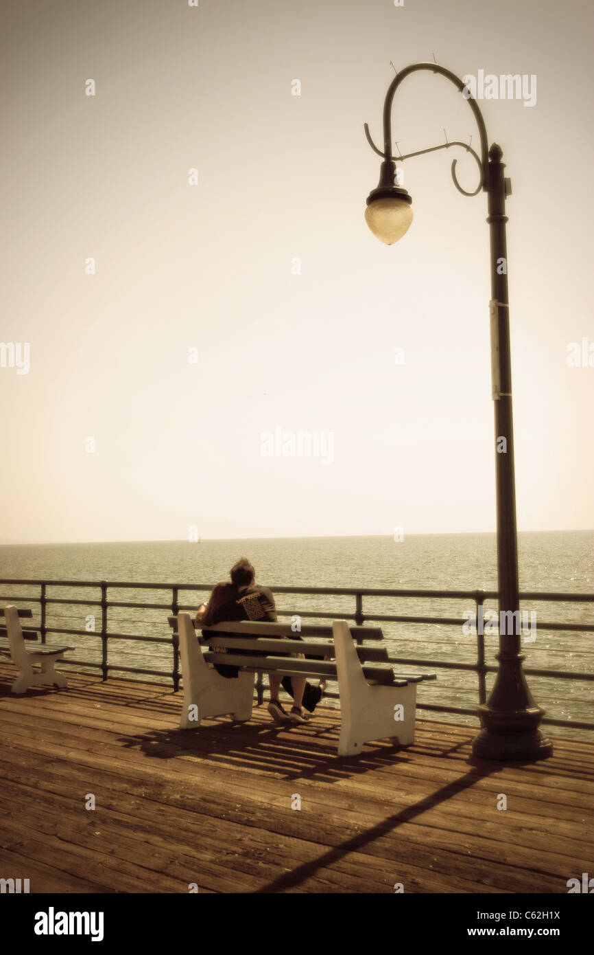 Two people on a date watching a sunset at the ocean Stock Photo