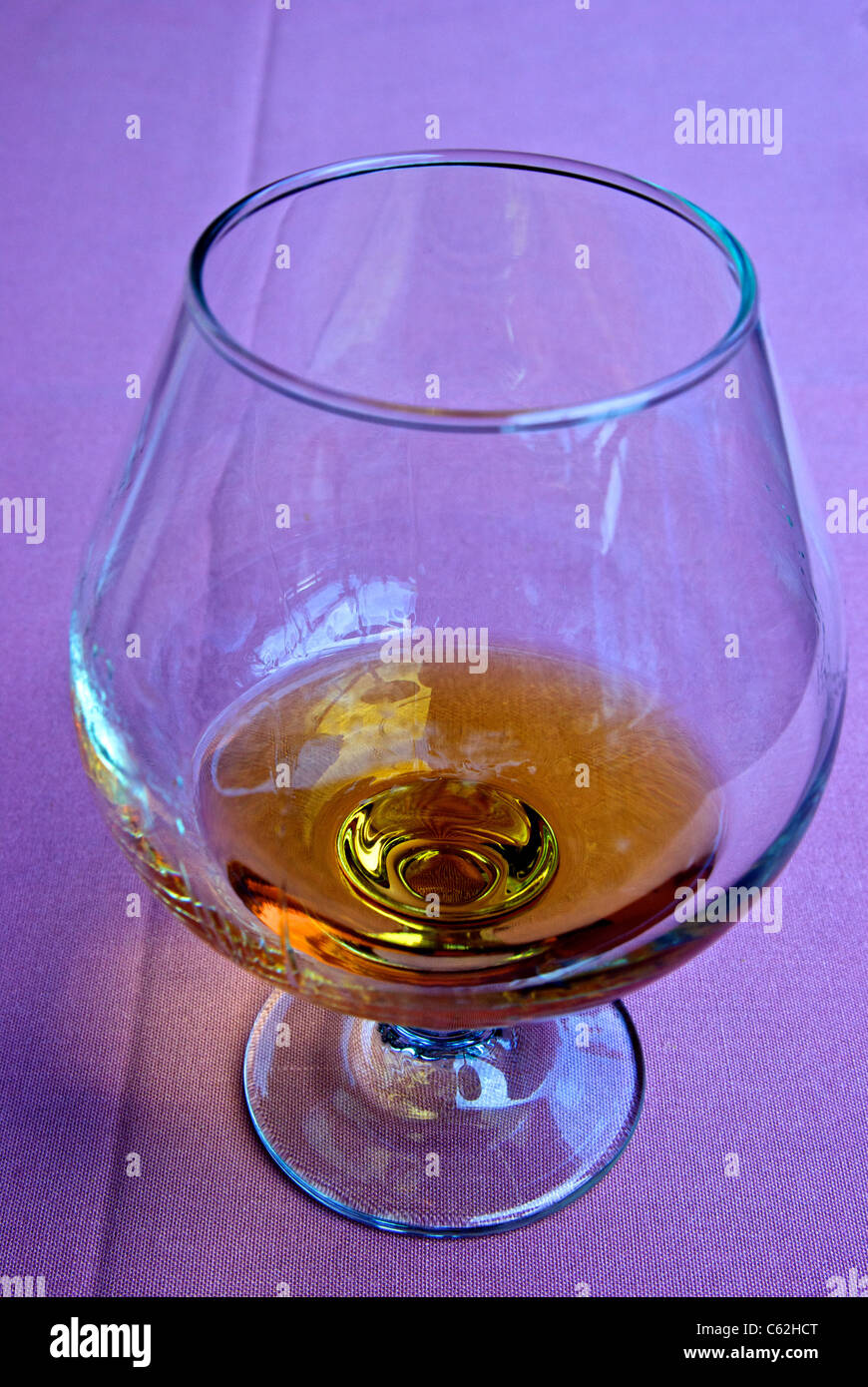Snifter glass Armagnac distilled brandy mauve tablecloth Stock Photo