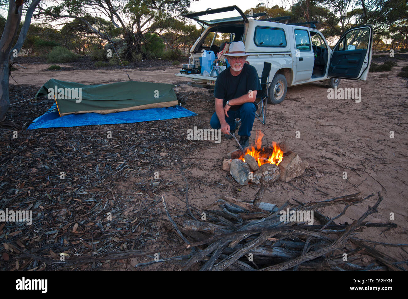 Man with campfire and pitched swag in the Australian outback Stock Photo